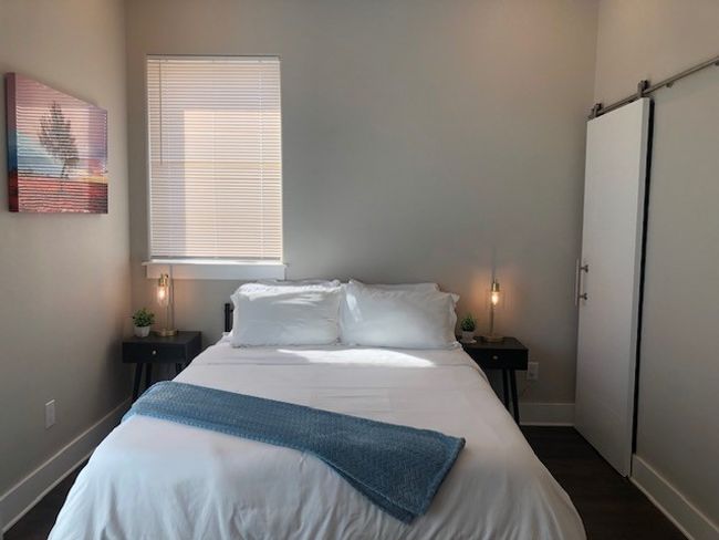Bedroom with dark wood finished floors, a barn door, and baseboards | Image 11