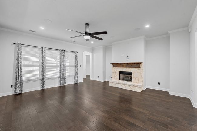 Unfurnished living room with a ceiling fan, recessed lighting, wood finished floors, arched walkways, and a fireplace | Image 7