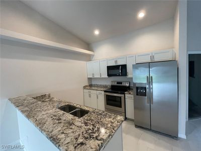 Kitchen featuring sink, kitchen peninsula, vaulted ceiling, white cabinets, and appliances with stainless steel finishes | Image 3