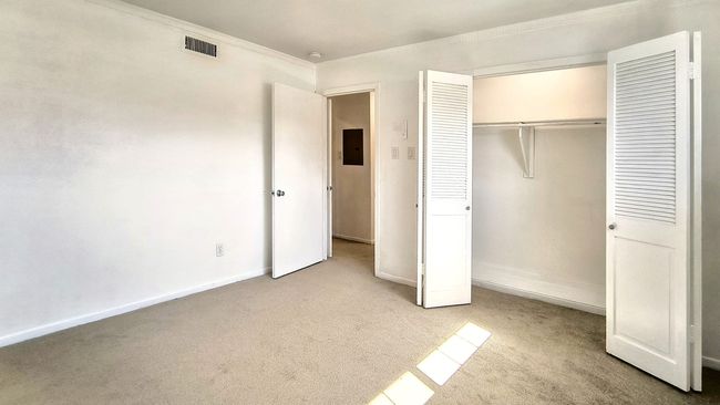 Unfurnished bedroom featuring crown molding, light carpet, electric panel, and a closet | Image 20