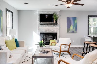 Living room with plenty of natural light, LVP flooring, brick fireplace, and ceiling fan | Image 3