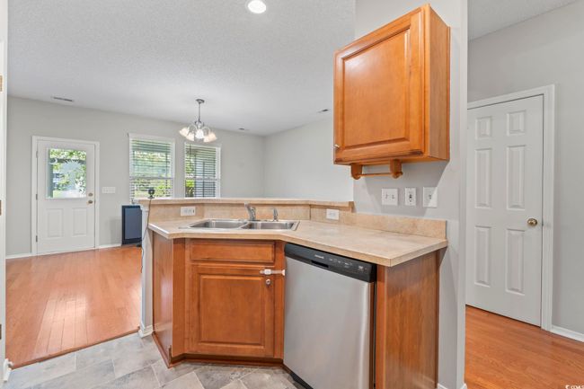 Kitchen featuring dishwasher, a sink, light countertops, a chandelier, and a peninsula | Image 11