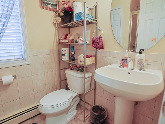 Bathroom with a wainscoted wall, a baseboard radiator, toilet, and tile walls | Image 19