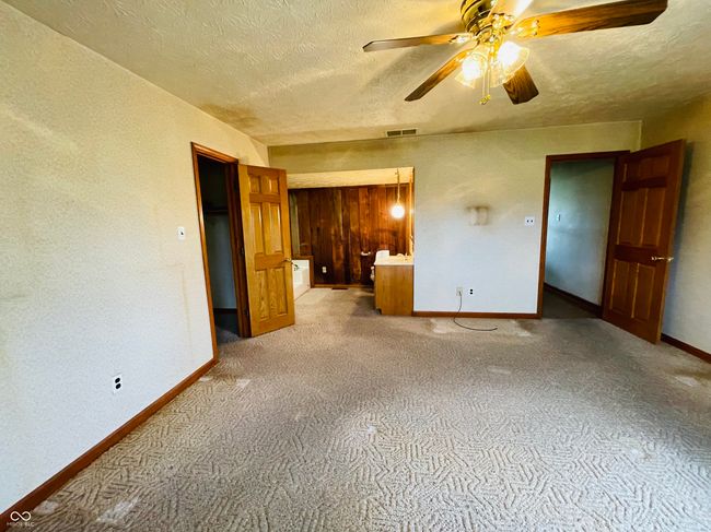 unfurnished bedroom with a textured ceiling, carpet, baseboards, and a ceiling fan | Image 22