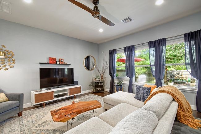 The living room features a modern ceiling fan, recessed lighting, and a serene backyard view. | Image 7