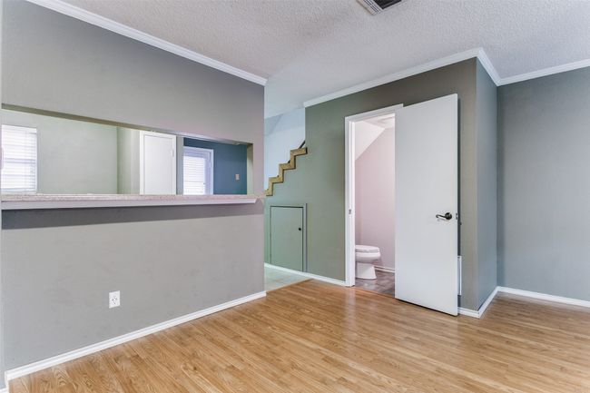 Spare room featuring ornamental molding, wood finished floors, a textured ceiling, and stairs | Image 10