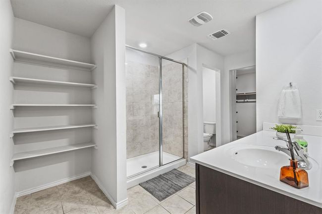Bathroom featuring a shower stall, vanity, tile patterned flooring, and a spacious closet | Image 11