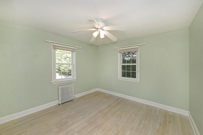Unfurnished room featuring baseboards, light wood-style flooring, radiator heating unit, and a ceiling fan | Image 12