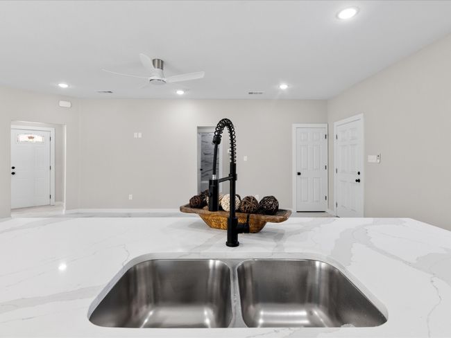 Details featuring visible vents, light stone counters, recessed lighting, a ceiling fan, and a sink | Image 12
