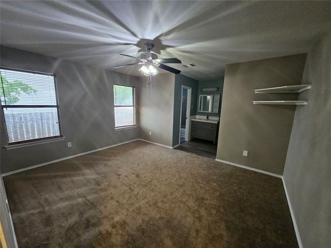 Unfurnished bedroom featuring baseboards, ensuite bathroom, a ceiling fan, and carpet floors | Image 19