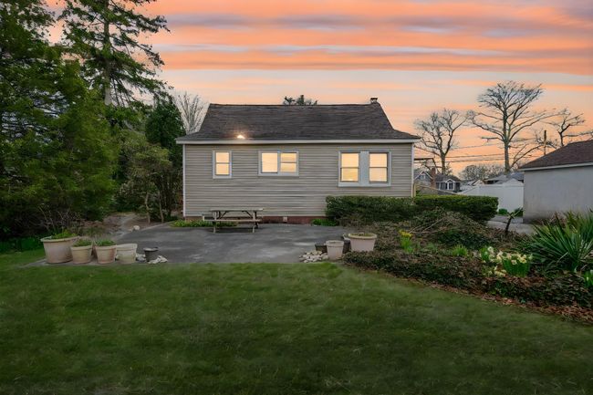 Back of house at dusk with a patio area, a shingled roof, and a yard | Image 7