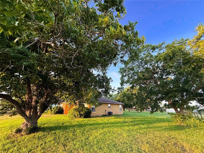 Charming single-story home with a cozy brick exterior, a small covered porch, and manicured bushes. Surrounded by lush greenery, it offers a serene and inviting atmosphere. | Image 18
