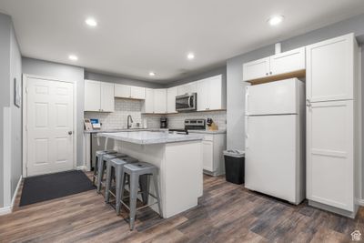 Kitchen with white cabinetry, appliances with stainless steel finishes, dark wood-type flooring, and a kitchen island | Image 3