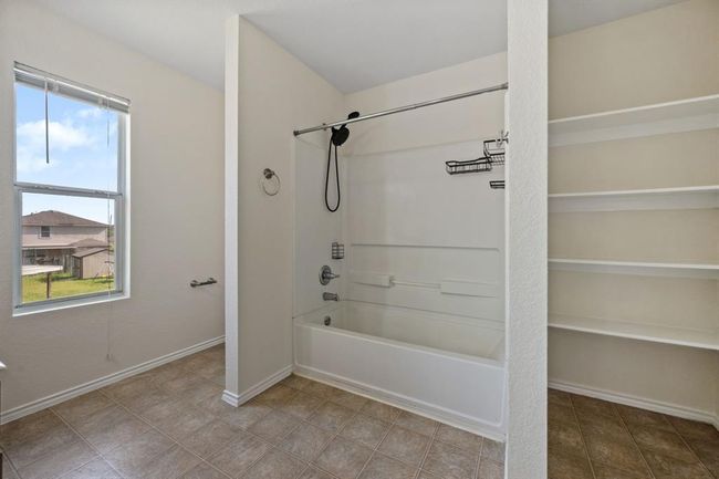 En-suite primary bath with a large vanity and tub/shower combo and built-in shelves. | Image 17