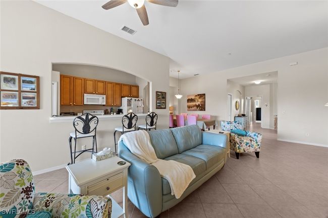 Living room with visible vents, a ceiling fan, baseboards, and light tile patterned floors | Image 15