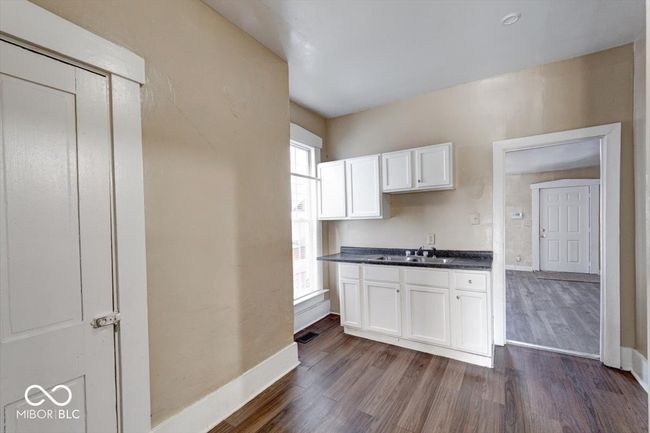 kitchen featuring a sink, dark wood-style flooring, white cabinetry, baseboards, and dark countertops | Image 6