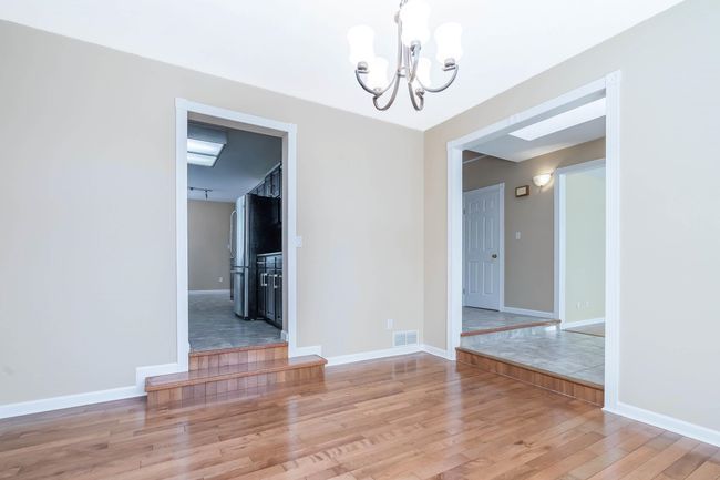 Unfurnished dining area featuring baseboards, visible vents, an inviting chandelier, and wood finished floors | Image 7