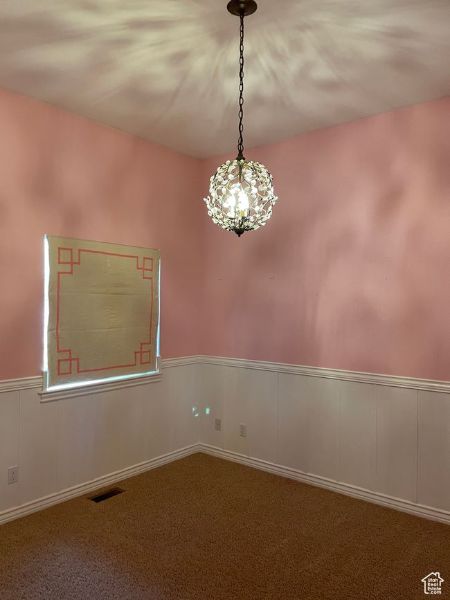 Spare room with carpet floors, wainscoting, and a chandelier | Image 13