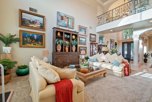 Living area featuring ornate columns, carpet, arched walkways, ornamental molding, and a high ceiling | Image 20
