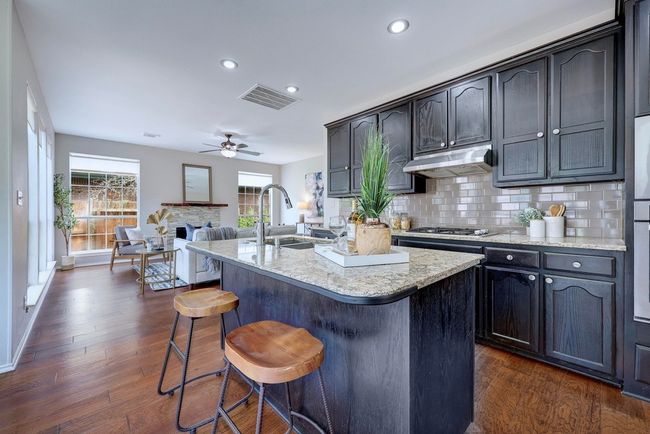 Kitchen with a sink, a ceiling fan, a kitchen breakfast bar, tasteful backsplash, and dark wood finished floors | Image 9