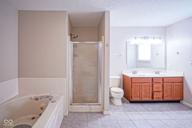 bathroom with a stall shower, a whirlpool tub, tile patterned flooring, double vanity, and a textured ceiling | Image 25