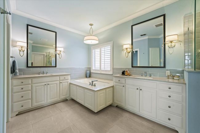 Bathroom with ornamental molding, two vanities, tile patterned floors, a bath, and tile walls | Image 24