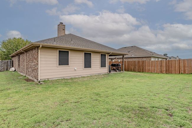 Back of property featuring a fenced backyard, a chimney, roof with shingles, and a lawn | Image 19