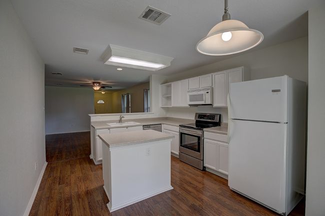Kitchen featuring some stainless steel appliances, a sink, a peninsula, open shelves, and white cabinets | Image 24