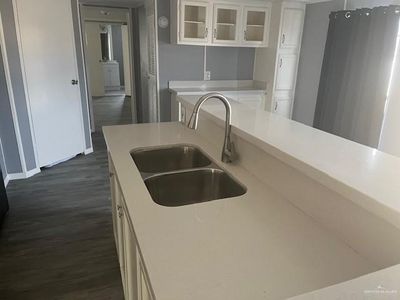 Kitchen with white cabinetry, sink, dark wood-type flooring, and stainless steel refrigerator | Image 3