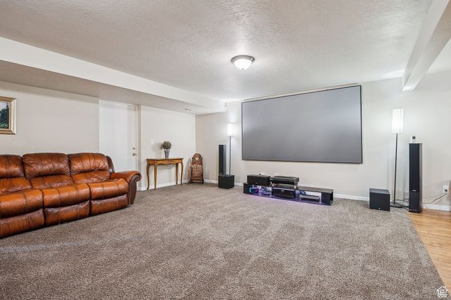 Cinema room featuring baseboards, a textured ceiling, and light colored carpet | Image 37
