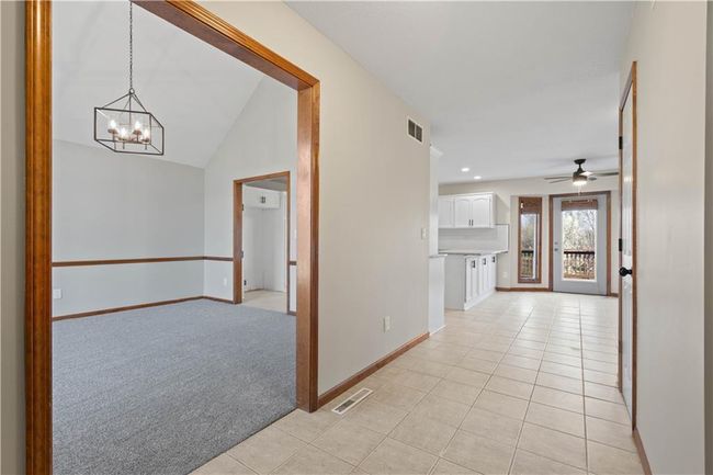 Hallway featuring a chandelier, baseboards, light tile patterned floors, and visible vents | Image 6