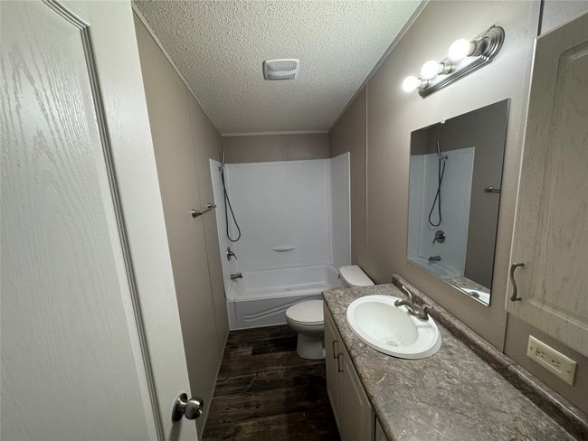 Full bath with wood finished floors, toilet, vanity, tub / shower combination, and a textured ceiling | Image 13