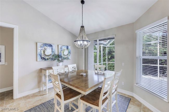 Dining space with light tile patterned floors, lofted ceiling, and a notable chandelier | Image 6