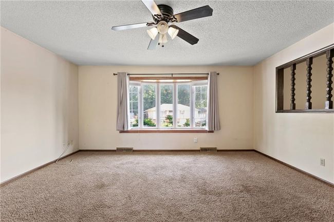 Empty room featuring a textured ceiling, carpet flooring, ceiling fan, and baseboards | Image 7