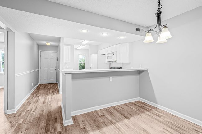 Kitchen featuring fridge, light wood finished floors, white cabinetry, white microwave, and a textured ceiling | Image 15