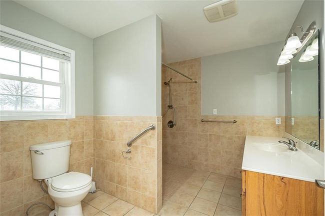 Full bathroom featuring tile patterned floors, visible vents, tiled shower, and tile walls | Image 24