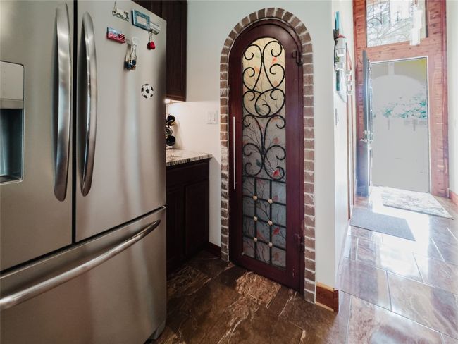 Kitchen featuring freestanding refrigerator, arched walkways, light stone counters, and dark marble finish floors | Image 26