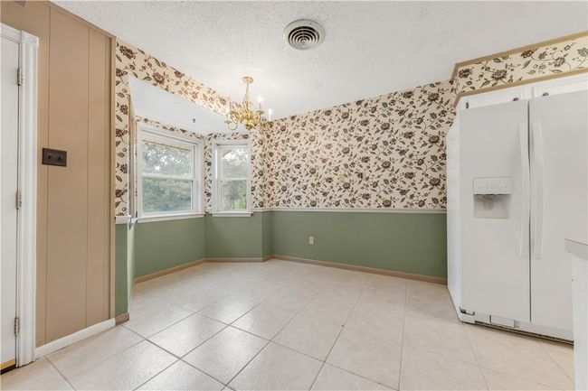 Unfurnished dining area with wallpapered walls, a chandelier, and a textured ceiling | Image 5