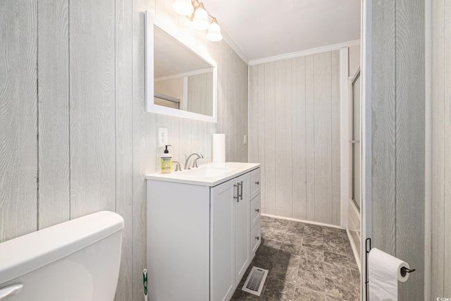 Full bathroom with wooden walls, vanity, bath / shower combo with glass door, and crown molding | Image 22