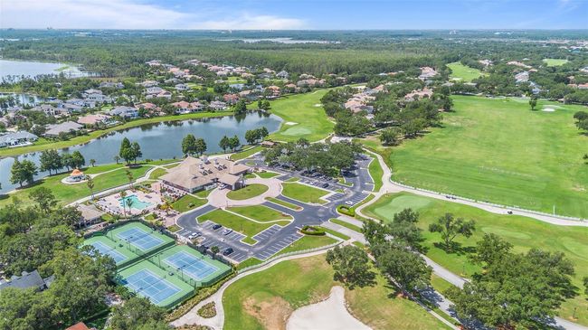 This stunning aerial view showcases the Golden Bear Club at Keene’s Pointe, a premier private club centered around a Jack Nicklaus Signature Golf Course. The image captures the full resort lifestyle—featuring championship tennis courts, a spacious resort-style pool, elegant clubhouse, lakeside walking paths, and sprawling fairways—all nestled among luxury homes and serene lakefront vistas. | Image 35