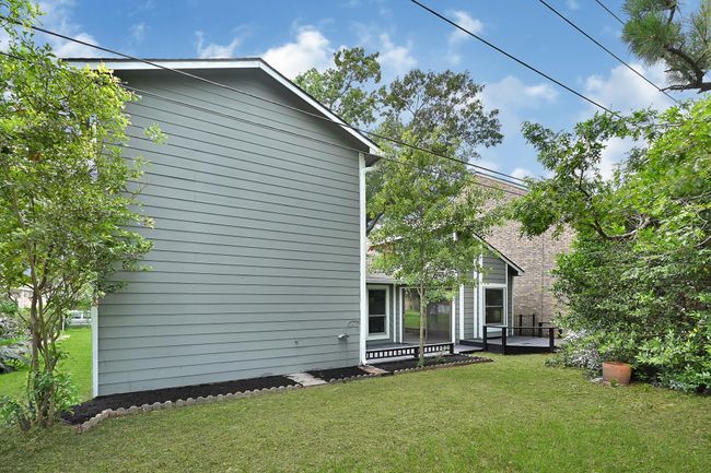 This view of the backyard showcases the home's peaceful setting along the golf course, surrounded by mature trees and fresh landscaping. The expansive green space and freshly painted deck offer an inviting place to relax or entertain while enjoying scenic fairway views and added privacy. | Image 47