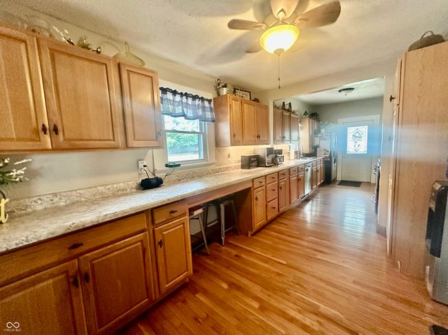 kitchen with light wood-type flooring, light countertops, ceiling fan, and a textured ceiling | Image 17