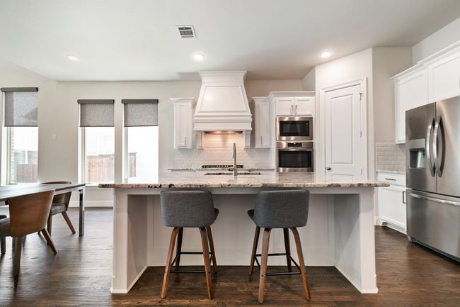 Kitchen with visible vents, dark wood finished floors, appliances with stainless steel finishes, an island with sink, and custom range hood | Image 13