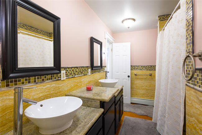 Bathroom with double vanity, tile walls, wainscoting, and a sink | Image 15