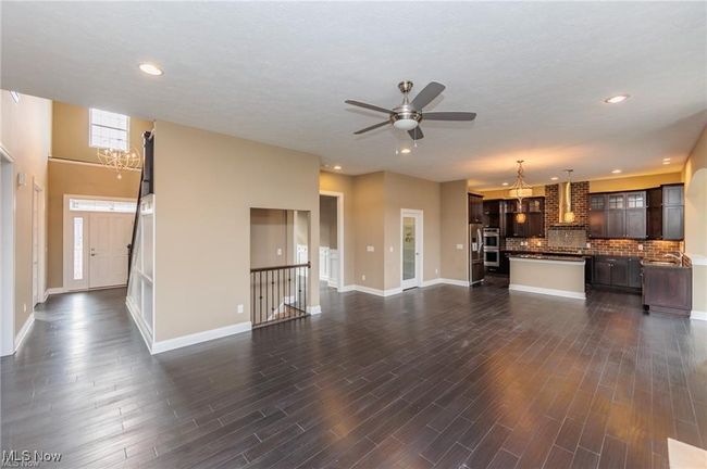 Unfurnished living room featuring recessed lighting, dark wood-style flooring, baseboards, and ceiling fan with notable chandelier | Image 14
