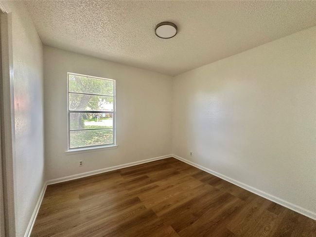 Empty room with a textured ceiling and dark wood-type flooring | Image 12