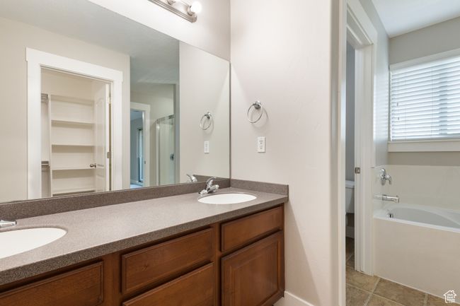 Bathroom featuring double vanity, a bath, a shower stall, a walk in closet, and tile patterned flooring | Image 16