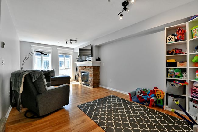 Interior space with rail lighting, a stone fireplace, baseboards, and wood finished floors | Image 8