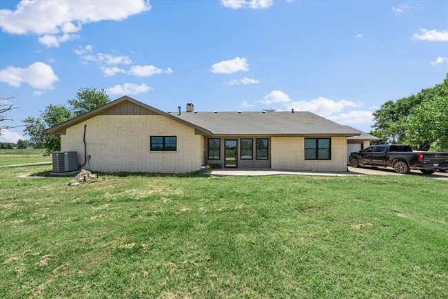 Rear view of house featuring cooling unit, brick siding, a patio area, and a lawn | Image 38