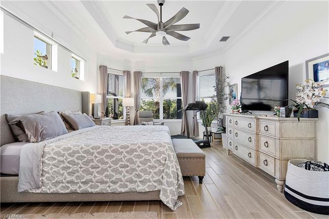 Bedroom featuring ornamental molding, a ceiling fan, a tray ceiling, and wood tiled floor | Image 45